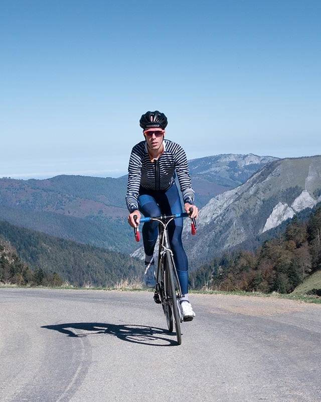 A cyclist riding uphill on a winding mountain road with breathtaking views, capturing the essence of adventurous and rewarding cycling holidays in nature.