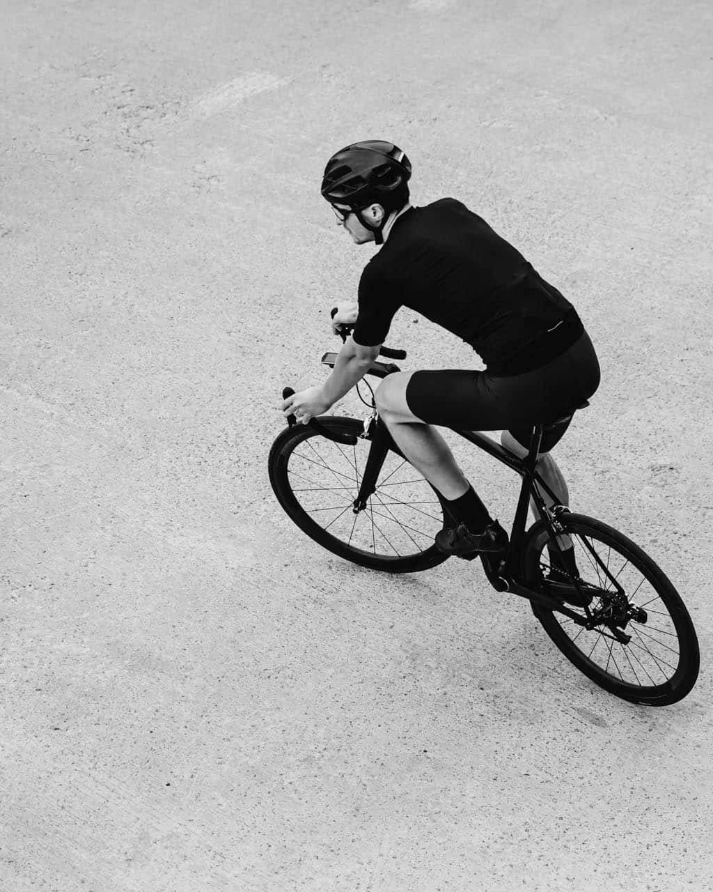 Black and white photo of sporty caucasian man in activewear and safety helmet riding bike outdoors. Concept of people and active lifestyles.