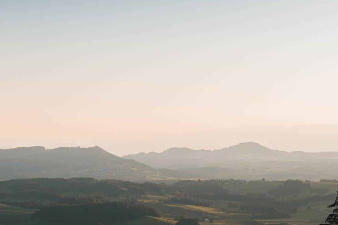 A picturesque Swiss landscape bathed in soft golden light, showcasing rolling green hills and distant peaks, perfect for serene cycling adventures.