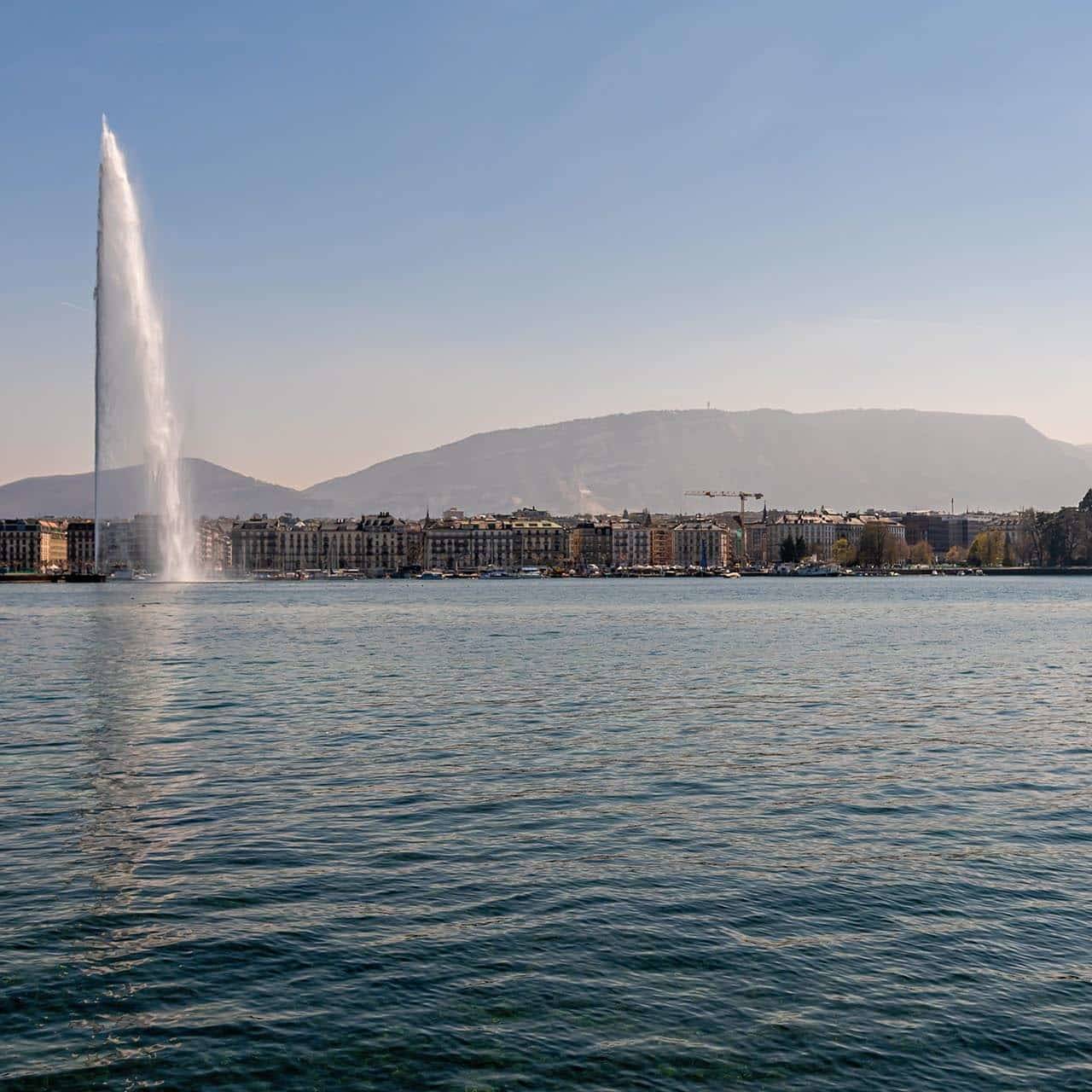 A scenic view of Lake Geneva with the famous Jet d'Eau fountain, part of the picturesque Geneva to Girona cycling tour.