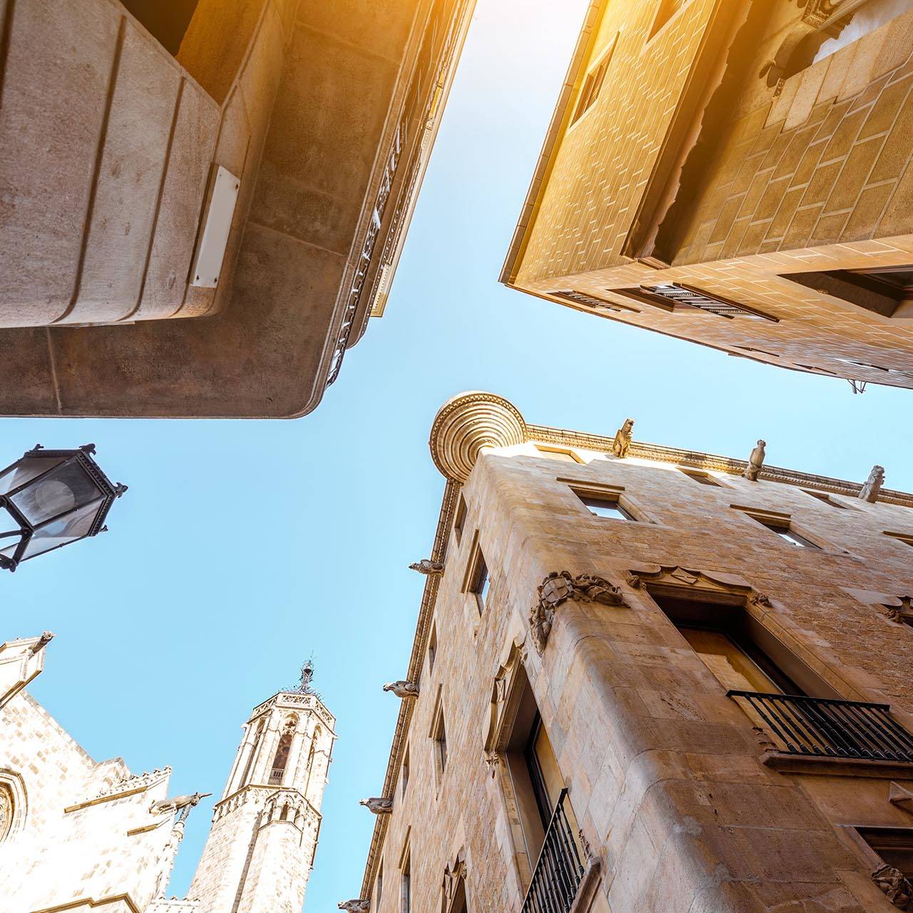 Upward view of historic buildings and cathedral in Girona under a clear blue sky, showcasing the charm of this popular Girona cycling destination.