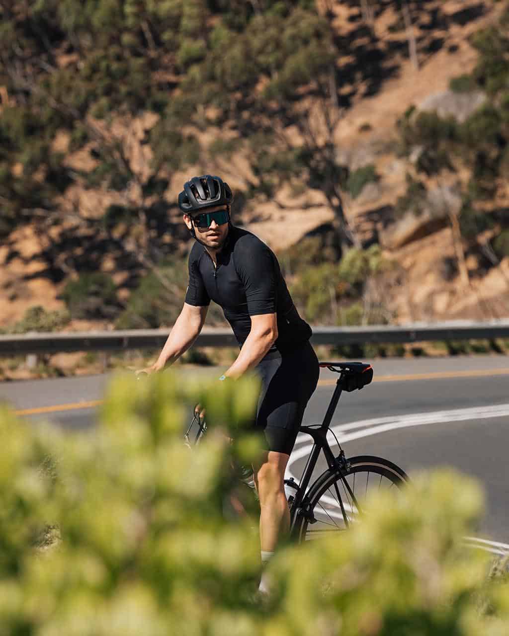 A solo cyclist riding along a winding road surrounded by trees and hills, perfect for cycling holidays for single travellers seeking adventure and scenic routes.