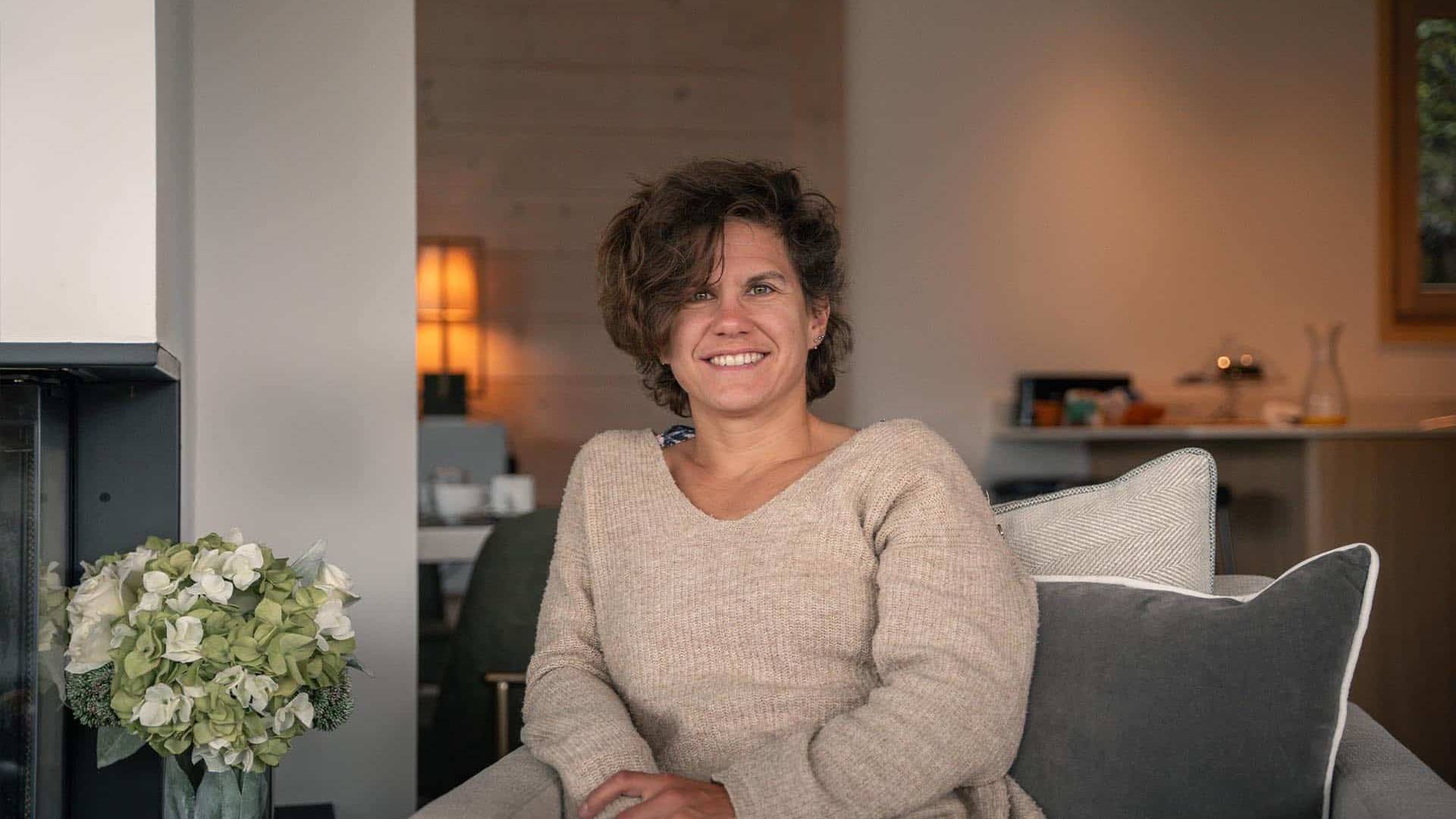 Woman sitting comfortably on a cozy armchair in a warmly lit living room.