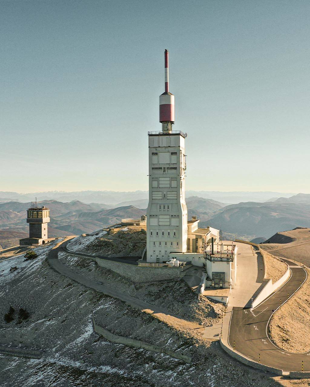 Mont Ventoux summit with its iconic tower, surrounded by rugged terrain and expansive views of the distant mountains.