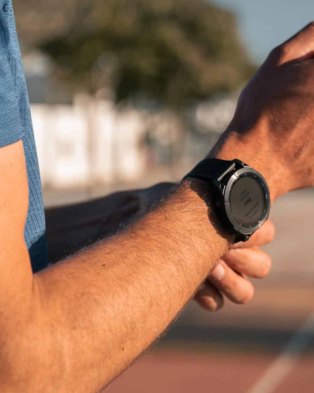 Close-up of a man adjusting his Garmin smartwatch before a workout.