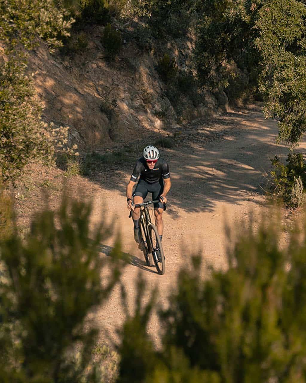 Cyclist tackling a rugged dirt trail surrounded by lush greenery, perfect for gravel bike adventures.
